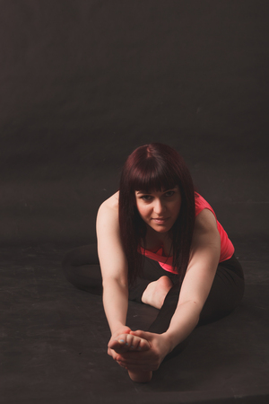 Woman doing stretching exercises over black backgroundの写真素材