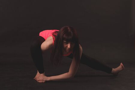 Woman doing stretching exercises over black background