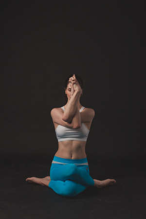 Beautiful sporty yogi girl practices yoga asana over black background