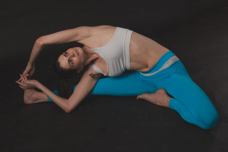 Beautiful sporty yogi girl practices yoga asana over black backgroundの写真素材