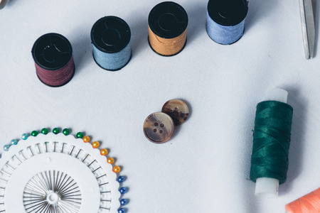 Sewing background. Accessories for needlework on white cloth background. scissors, buttons, measuring tape, sewing supplies. Set for needlework top view.の写真素材