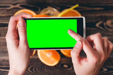 Hands Taking Photo of Juice and Oranges on Wooden Background. Green Screen. Technology Concept