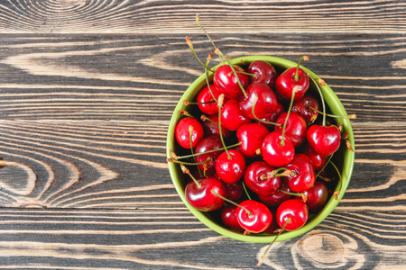 Red Cherries in the Green Cup on Wooden Table, Fruits, Berries Healthy Food Conceptの写真素材