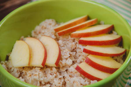 Oatmeal Porridge with Apple Slices in Green Bowl. Healthy Food Conceptの写真素材