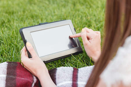 Closeup of Girl Searching Information on Web Page via Digital Tablet during her Rest in the Fresh...