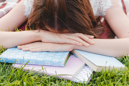 Girl Tired of Studying and Lying with Books on Green Grass. Education Conceptの写真素材
