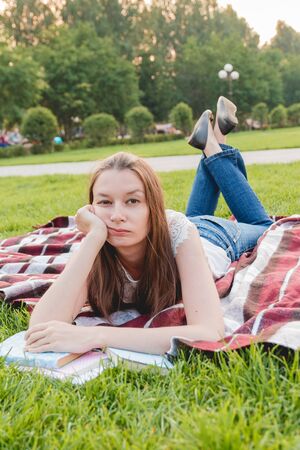 Girl Tired of Studying and Lying with Books on Green Grass. Education Concept