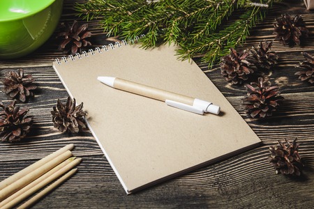 view of notebook in the center of cute Christmas decoration, cones, fir tree branchの写真素材