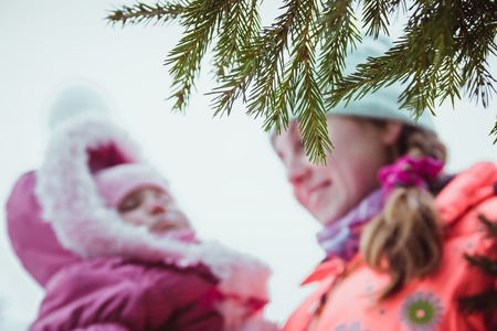 happy family mother and baby girl daughter playing and laughing in winter outdoors in the snowの写真素材