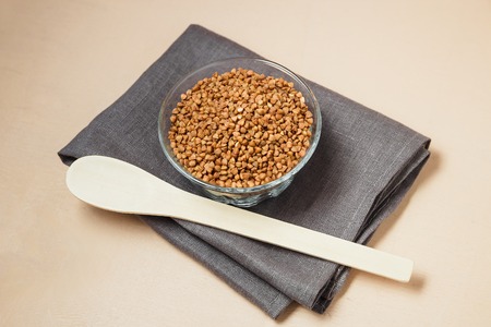 Buckwheat groats in bowl and wooden spoonの写真素材