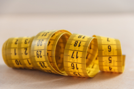Curved measuring tape. Closeup view of yellow measuring tape.
