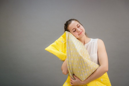 pretty young woman with yellow blanketの写真素材