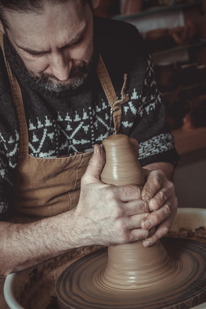 elderly man making pot using pottery wheel in studioの写真素材