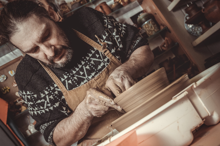 elderly man making pot using pottery wheel in studioの写真素材