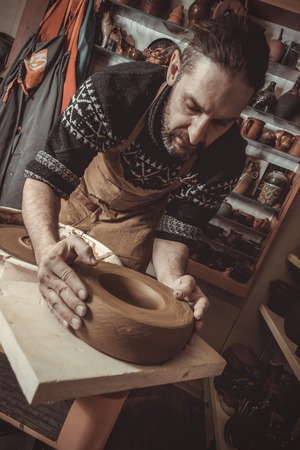 elderly man making pot using pottery wheel in studioの写真素材