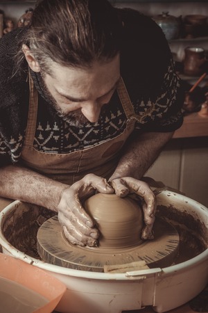 Adult male potter master mashing the clayの写真素材