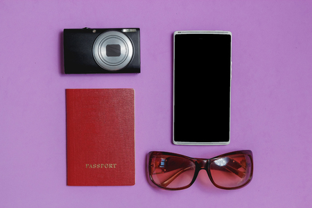 Smartphone, Passport, Sunglasses, Photo Camera on lilac Background. Top View Travel Concept Mock up.の写真素材