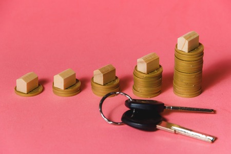 House Models On Top Of Increasing Stacked Coins Over Pink Background. Mortgage Concept with...