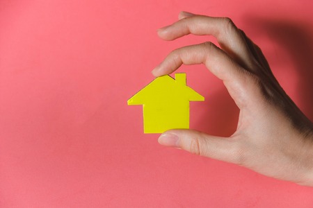 Female Hands Holding Yellow Paper House, Homeless Housing Shelter and Real Estate , Family House Insurance Concept.の写真素材