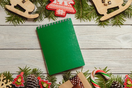 White wooden christmas background with fir branches, cones, decor, notebook, top view, copyspace.の写真素材