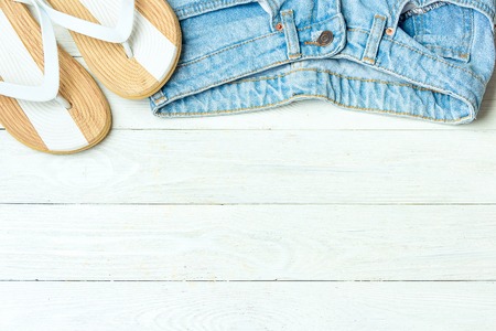 Frame elegant slippers jeans on white wooden background, copyspace for text, summer vacation.の写真素材