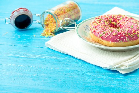 Donut on plate, kitchen towel and on blue wooden table. Photo of sweets with copyspace.の写真素材