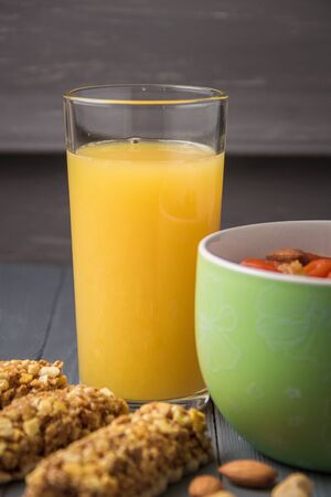 Granola cereal flakes with dried fruit, nuts in green bowl on gray wooden table.の写真素材