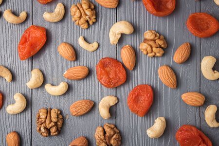 Assortment of nuts and dries fruits on gray wooden table. Cashew, hazelnuts, walnuts, almonds. Top view.の写真素材
