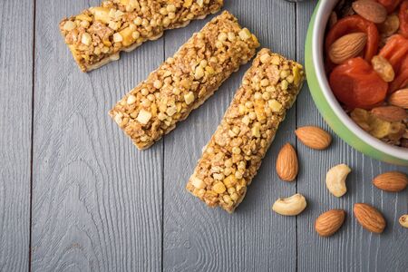 Granola cereal flakes with dried fruit, nuts in green bowl on gray wooden table. Top view with copyspace.の写真素材