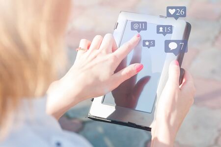 blogger holds tablet with flying social media icons of likes, comments, folowwers, stars. Illustration of network influence.の写真素材