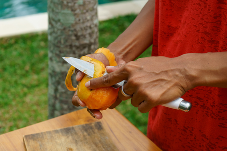 A local Indonesian girl peel yellow mango for making a fruit saladの写真素材