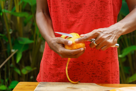 A local Indonesian girl peel yellow mango for making a fruit salad