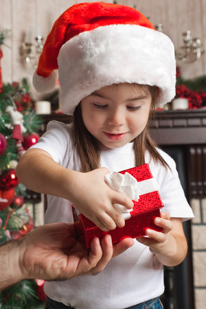 Christmas gift from father for little girl in Santa hatの写真素材