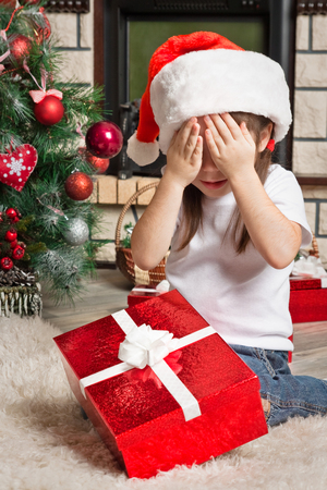 Little girl with  closed eyes in Santa hat with Christmas giftの写真素材