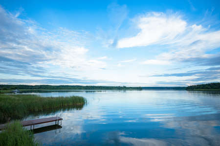 view of the river from the shore with a beautiful sky and cloudsの写真素材
