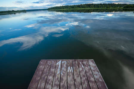 view of the river from the shore with a beautiful sky and cloudsの写真素材
