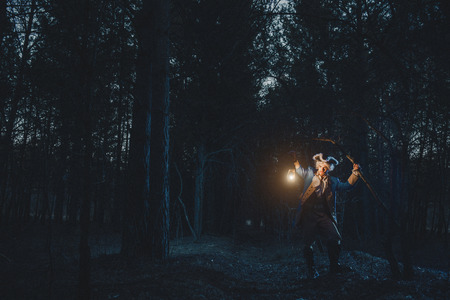 Man dressed as a courtier or officer 17-18 age in night forest. Lighting his way with lanternの写真素材