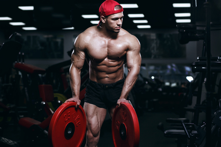 Muscular athletic bodybuilder fitness model posing and exercises in gymの写真素材