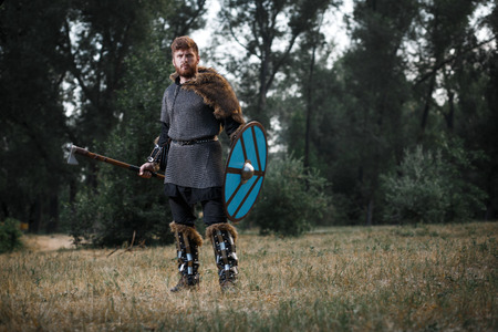 Warrior Viking in full arms with axe and shield in dark forest waiting for battleの写真素材
