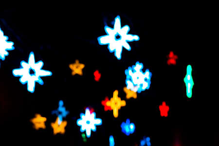 Colorful beautiful multi-colored Christmas blur stars lights on a black background
