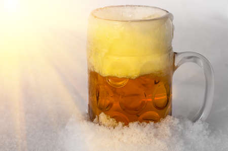 A mug of beer standing in the snow in the winterの写真素材