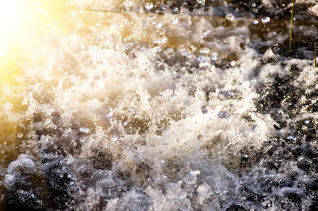 water under a stream of heavy rain during a thunderstorm with sprouting sunshineの写真素材