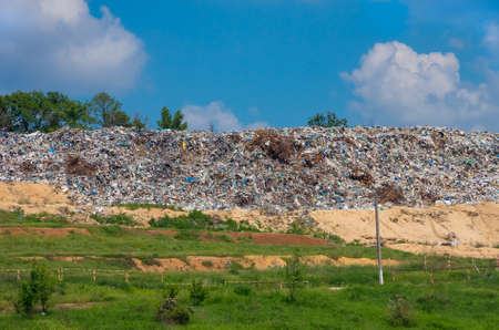 On landfill metal mountain, plastic and rubber is ready for recycling on a background of blue skyの写真素材