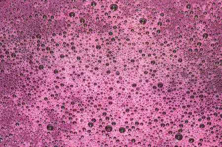 Bubbles on a red wine in the process of natural fermentation of the wort. alcoholic backgroundの写真素材