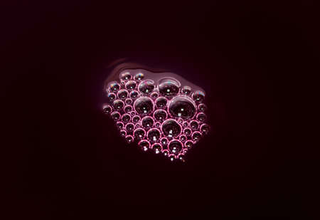 Bubbles on a red wine in the process of natural fermentation of the wort. alcoholic background