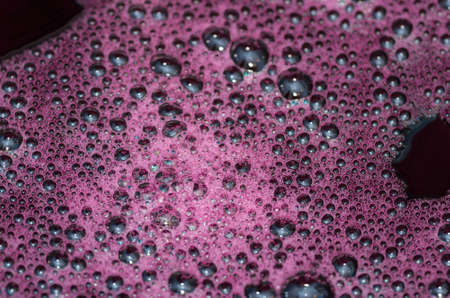 Bubbles on a red wine in the process of natural fermentation of the wort. alcoholic backgroundの写真素材