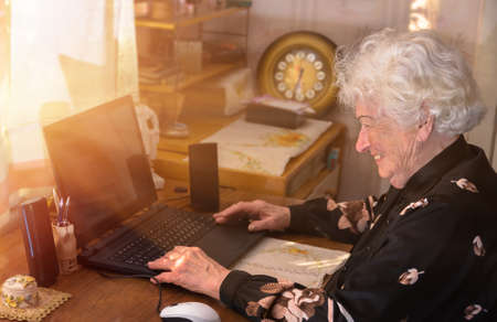 Grandmother learns to work at home on the computer and internetの写真素材