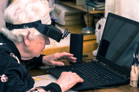 grandmother learns to work at home on the computer and internet In big special glasses virual realityの写真素材