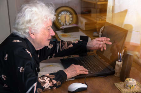 Grandmother learns to work at home on the computer and internetの写真素材