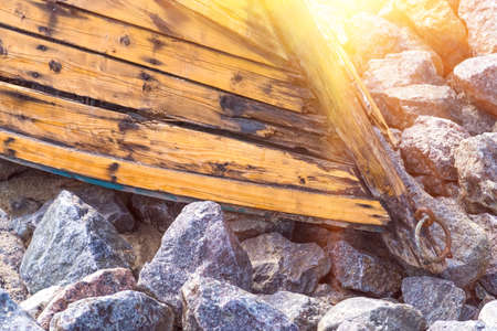 An old wooden boat lying on the stones closeup on the coastの写真素材